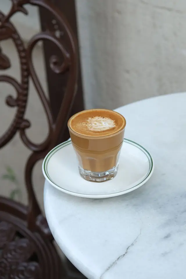 Cortado en vaso sobre una mesa de mármol